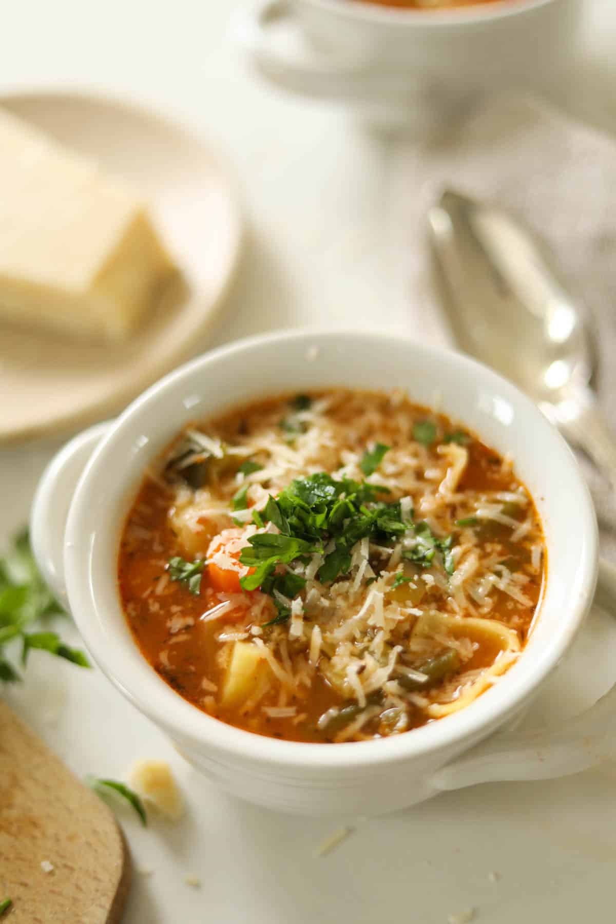 Soup and a silver spoon on a white countertop.