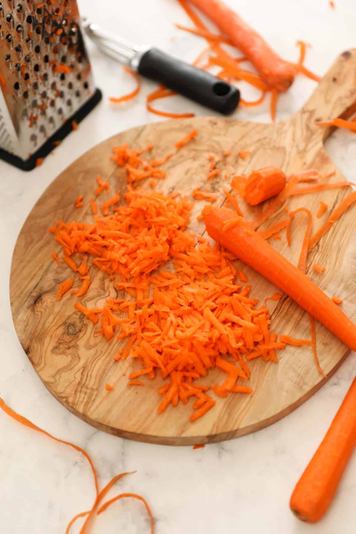 carrots being grated on a box grater