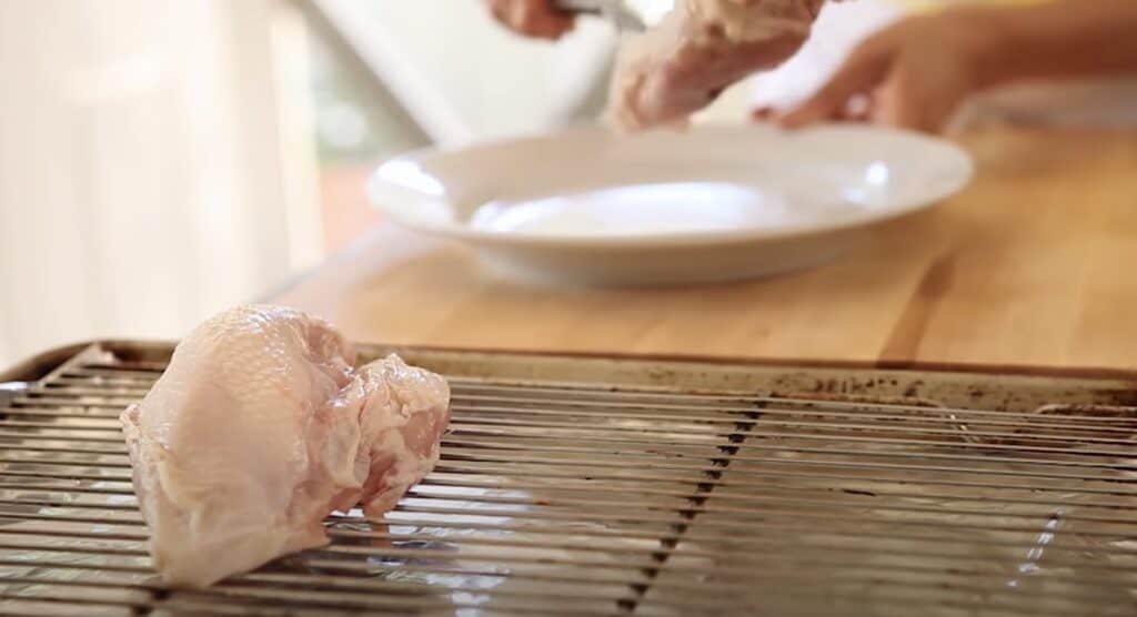 Placing raw chicken chicken breasts on a sheet pan to roast