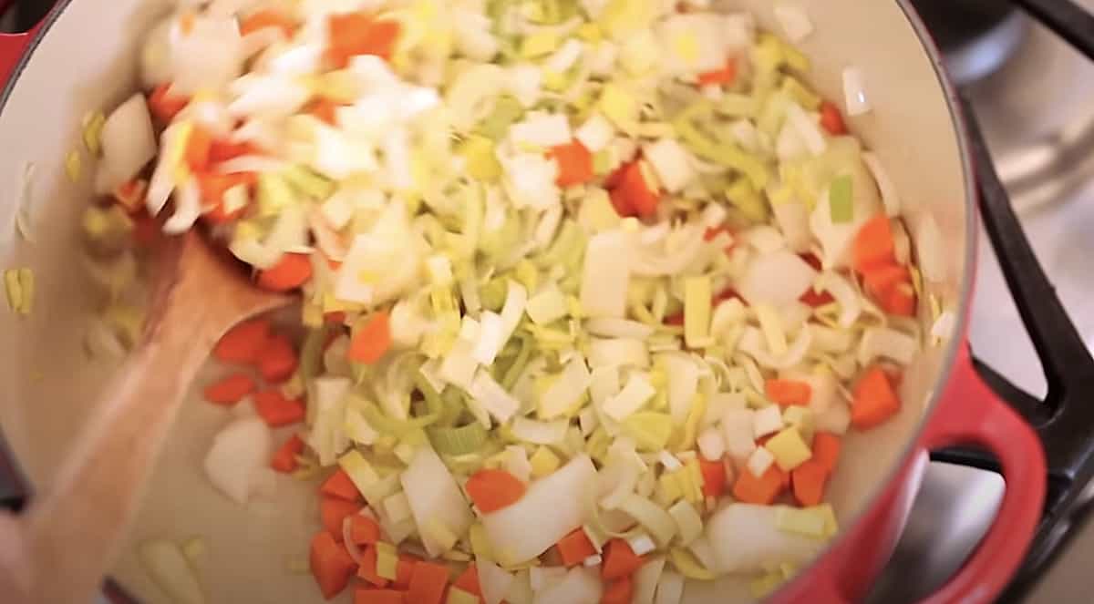 a mixture of leeks, carrots and white onion cooking in a Dutch oen