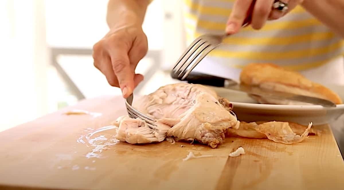 Shredding cooked chicken breast on a cutting board