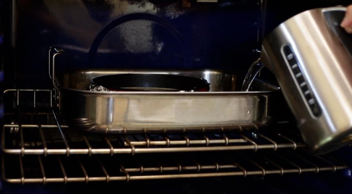 a person pouring hot water from a kettle into a roasting pan