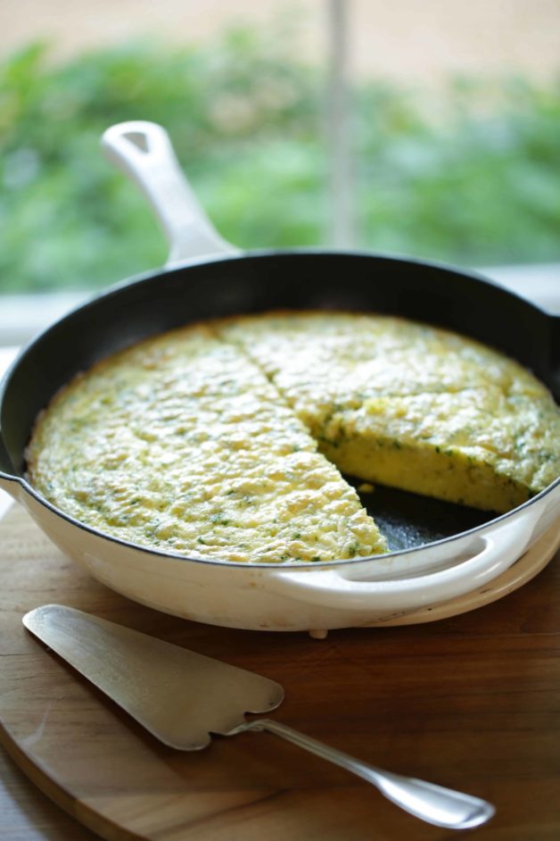An Egg Bake Casserole in a white skillet with 1 slice cut out 