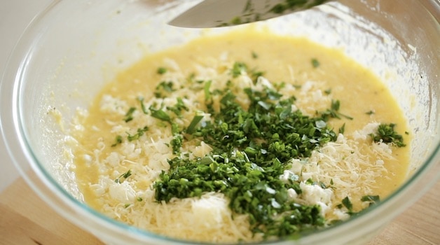 Adding chopped herbs with a chef's knife into an egg casserole batter