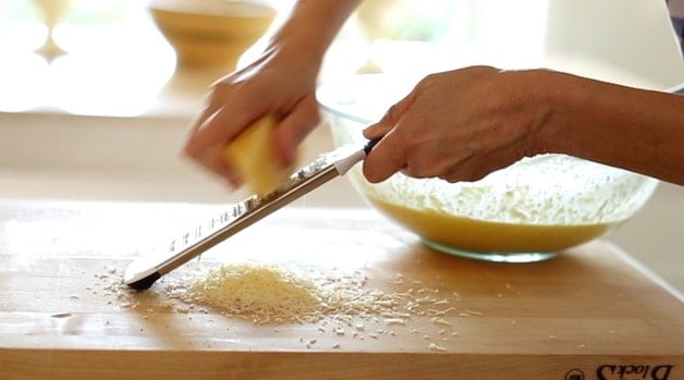 Grating fresh parmesean cheese onto a cutting board with a microplane