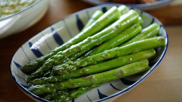 A blue and White Serving dish with a close up of roasted asparagus 