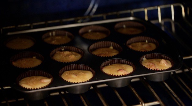 Placing strawberry muffins in the oven to bake