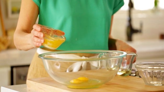 Adding melted butter to a larger mixing bowl with eggs in it