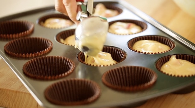 Spooning out muffin batter into a muffin tin lined with muffin papers