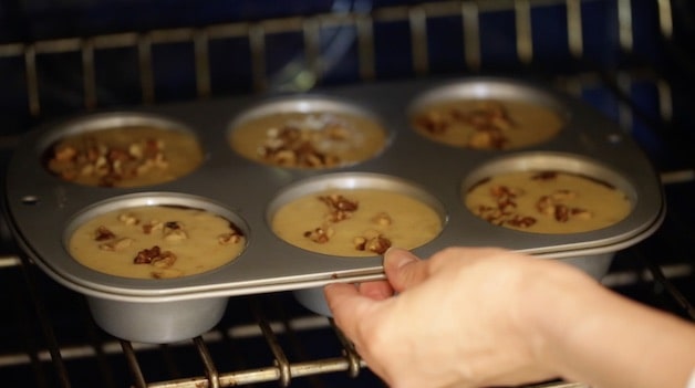 placing jumbo muffin tin filled with banana muffin batter into a oven
