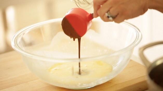 tempering eggs with warm chocolate from a measuring cup