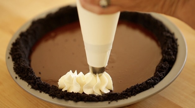 Piping whipped cream on a chocolate pie