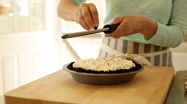 grating chocolate on a chocolate pie with whipped cream