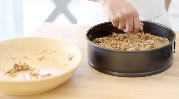 adding crumb topping to a cake batter in a cheesecake pan