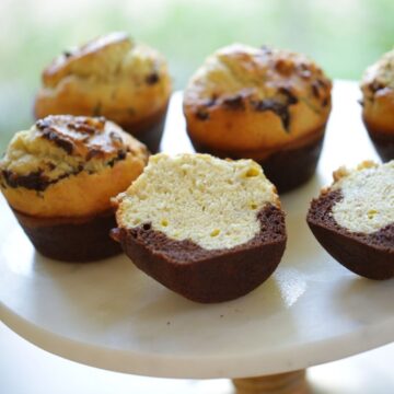 Black Bottom Banana Muffins on a cake stand sliced open