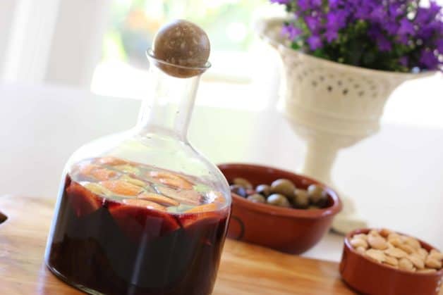 Red Wine Sangria in a decanter with olives and almonds in the background