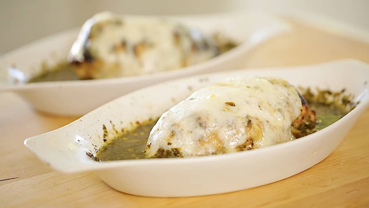 two gratin dishes with pesto sauce and chicken in it with melted mozzarella cheese on top