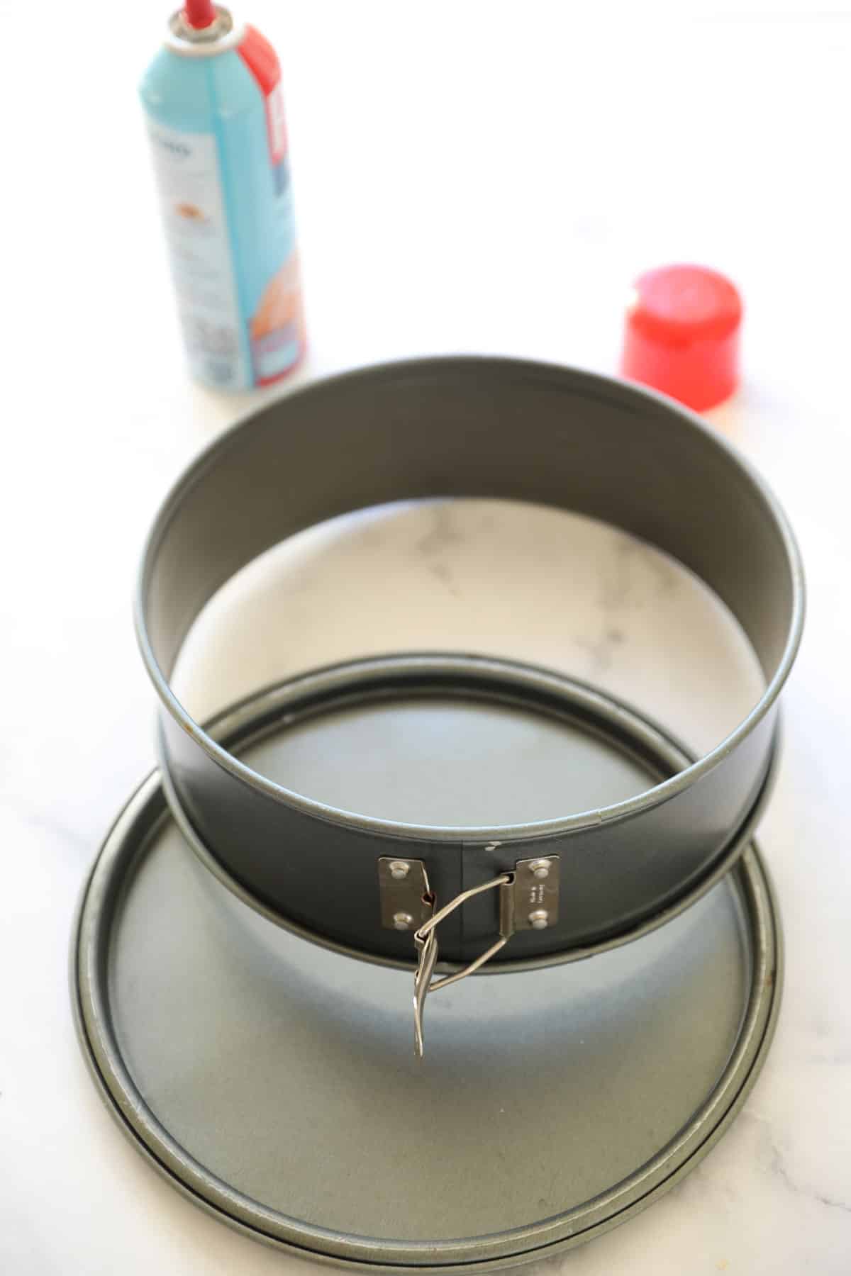 a cheesecake pan opened to show ring and baking spray