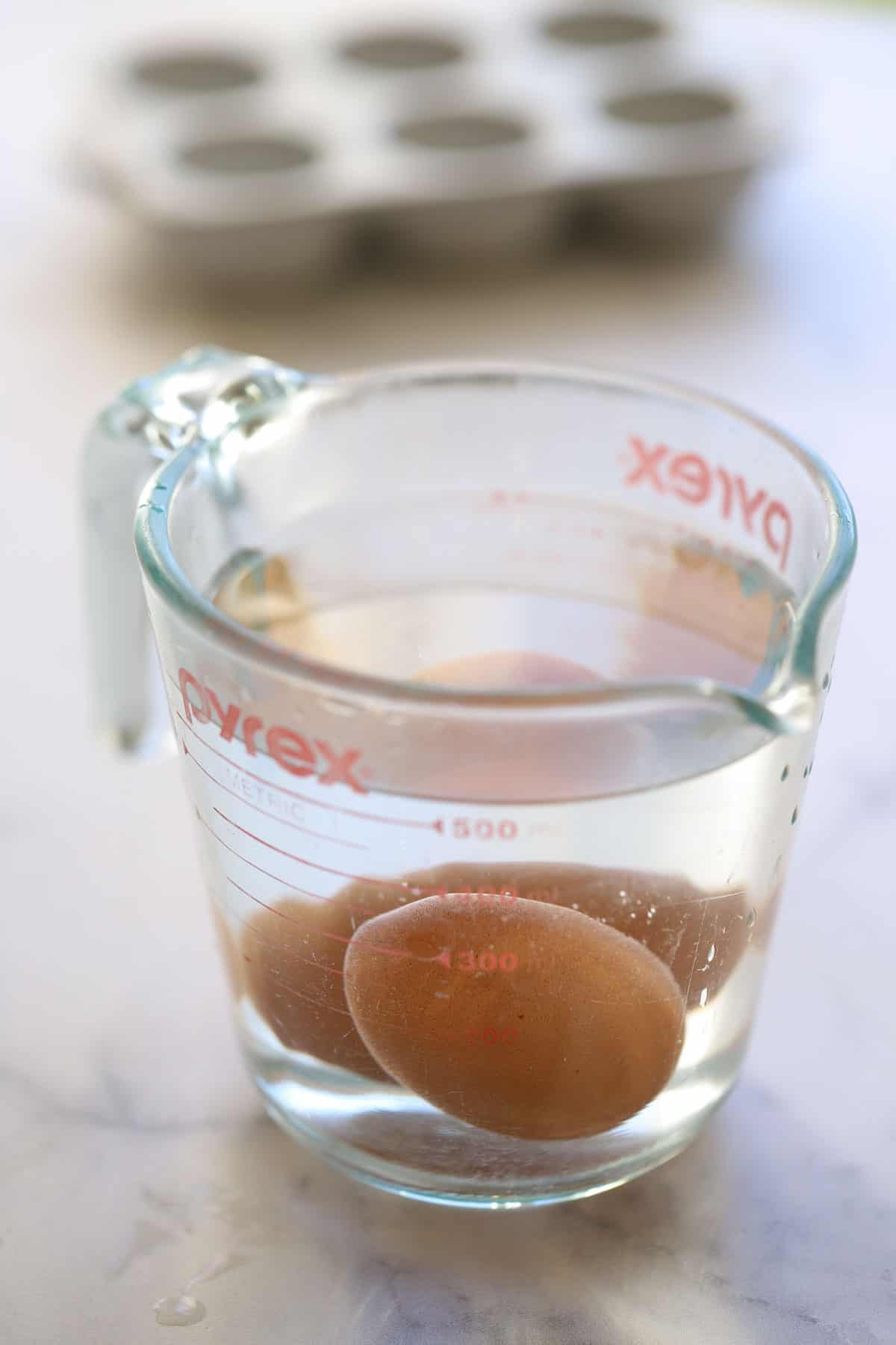 eggs submerged in warm water in a Pyrex pitcher