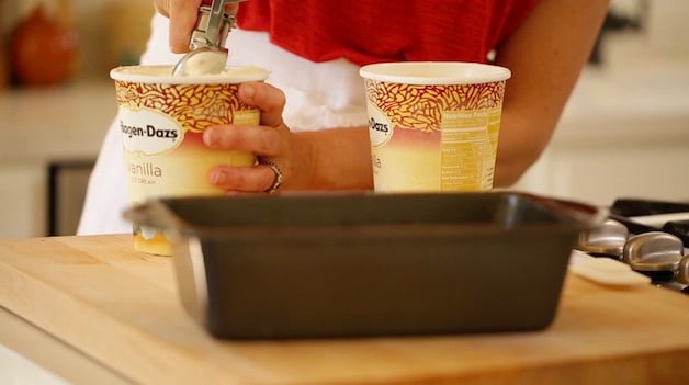 Scooping out vanilla ice cream into a loaf pan 