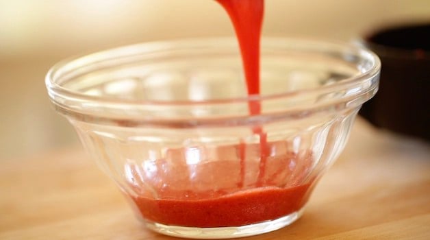 Pouring strawberry puree into a small glass bowl 