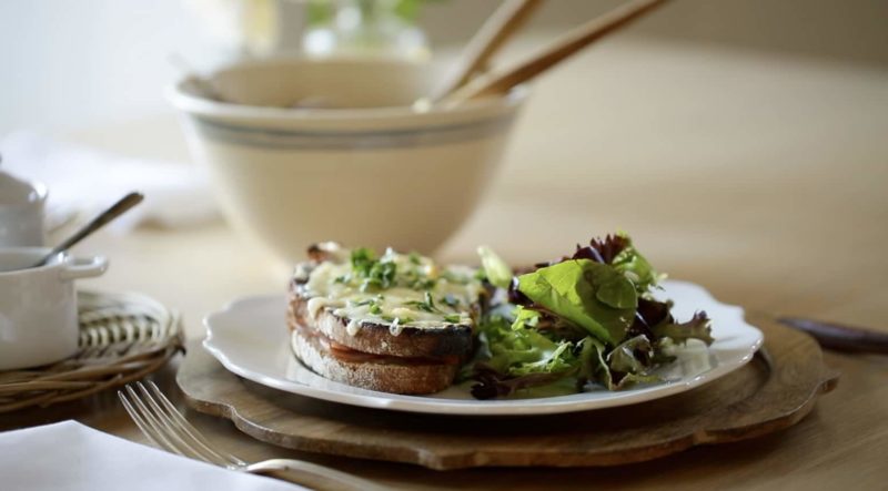 Croque Monsieur and Croque Madame Sandwiches with a green salad and a salad bowl in the distance