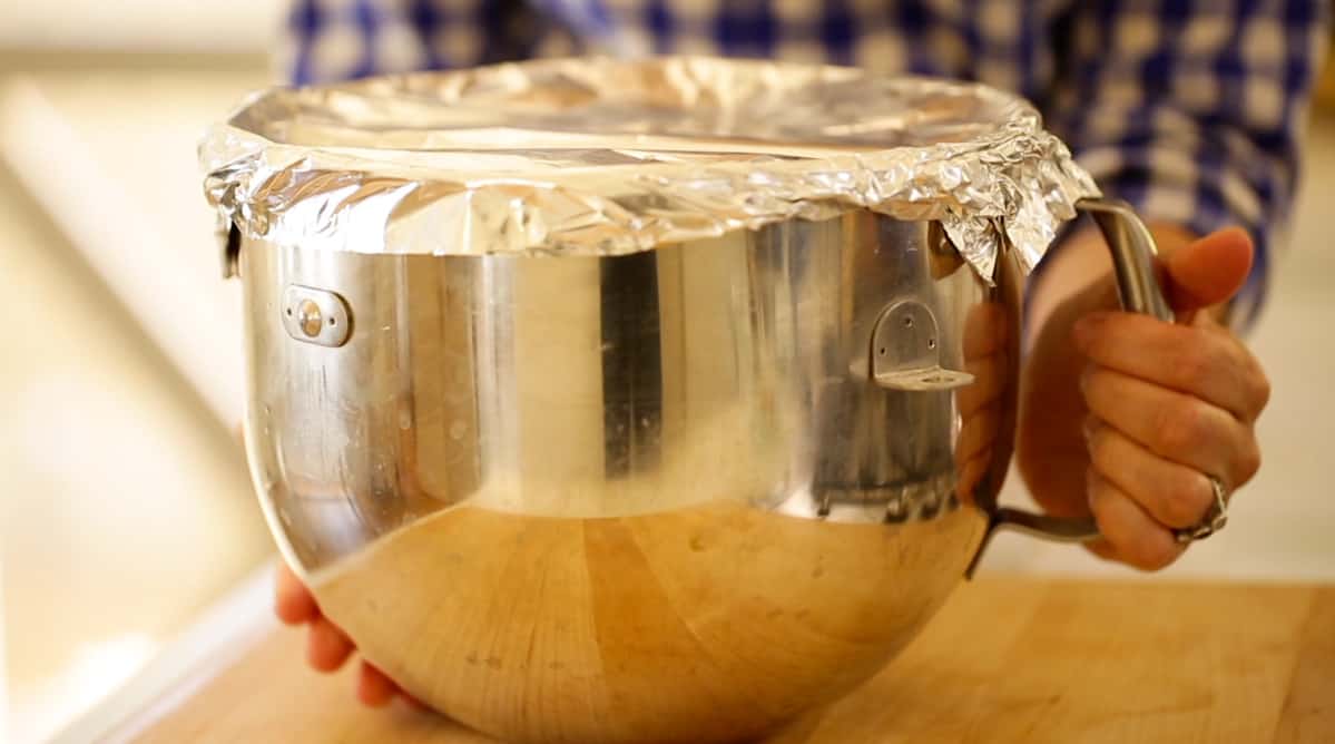 A metal mixing bowl covered with foil