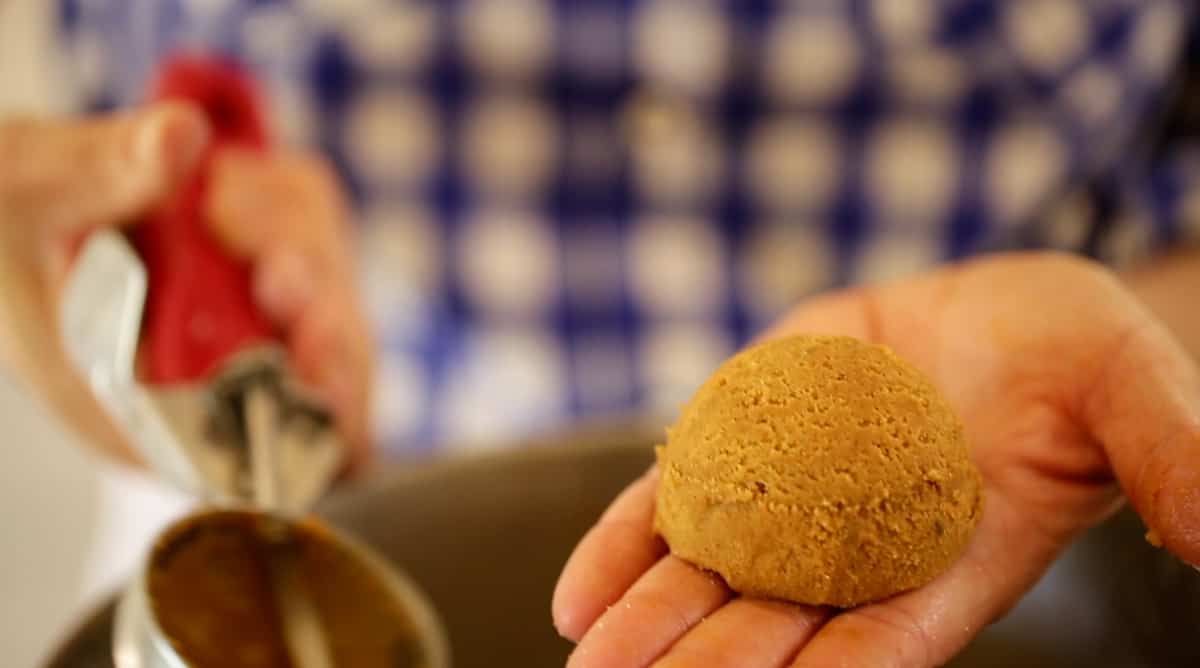 a ball of cookie dough in a person's hand with an ice cream scoop