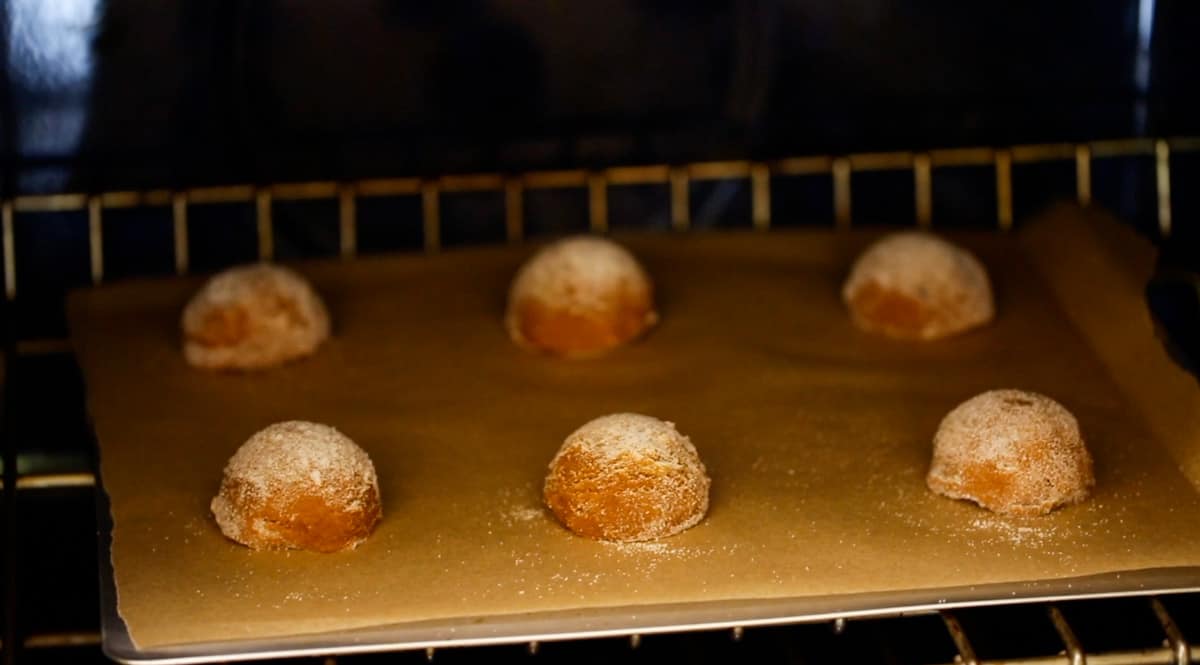 Baking cookie dough balls in oven on a baking sheet lined with parchment paper