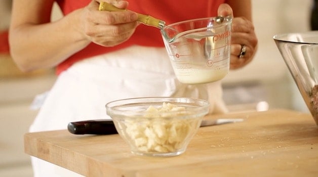 Adding milk to bread cubes in small bowl