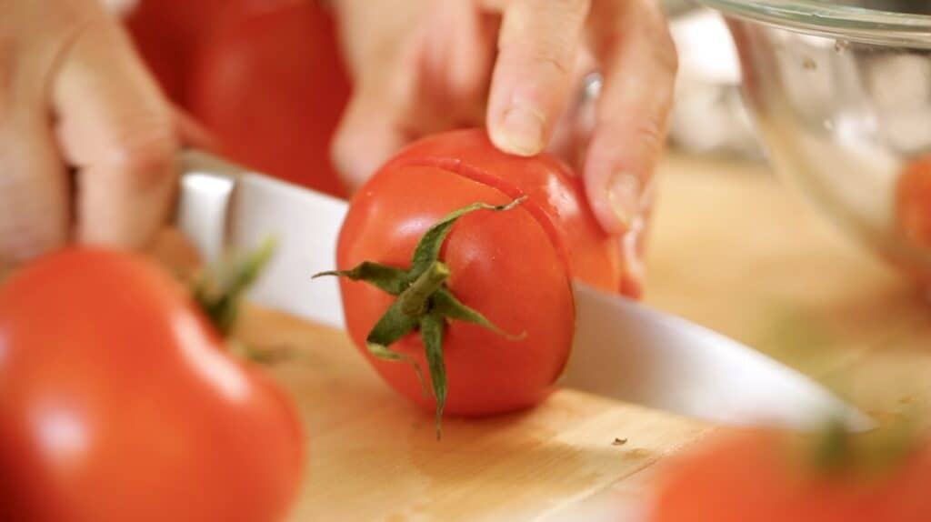 A tomato top being sliced off