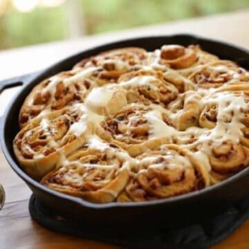 How to Make Cinnamon Rolls Recipe served in a cast iron skillet on a wood surface