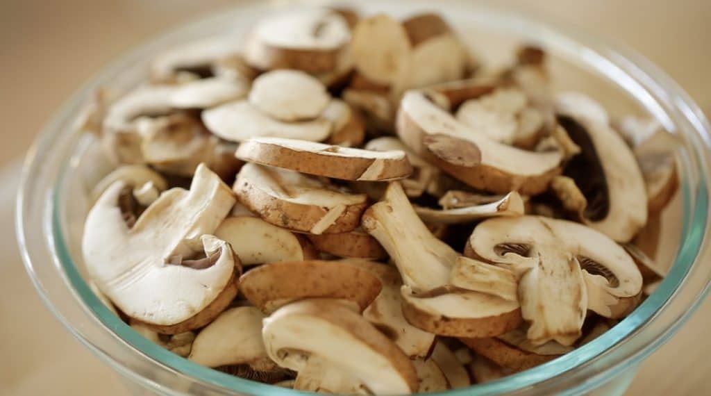 a glass bowl filled with sliced mushrooms