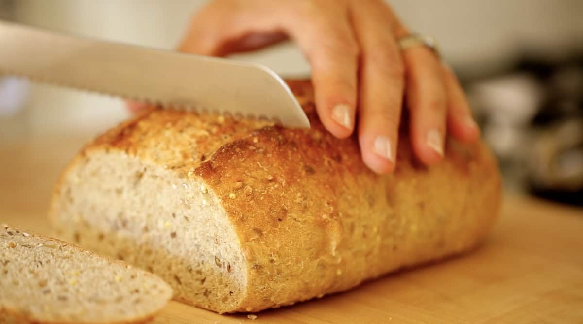 A close up of a person cutting a piece of bread