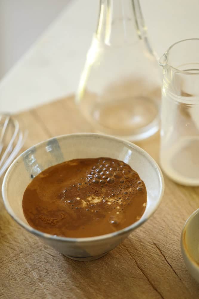 Espresso powder, hot water and milk, mixed in a small bowl.