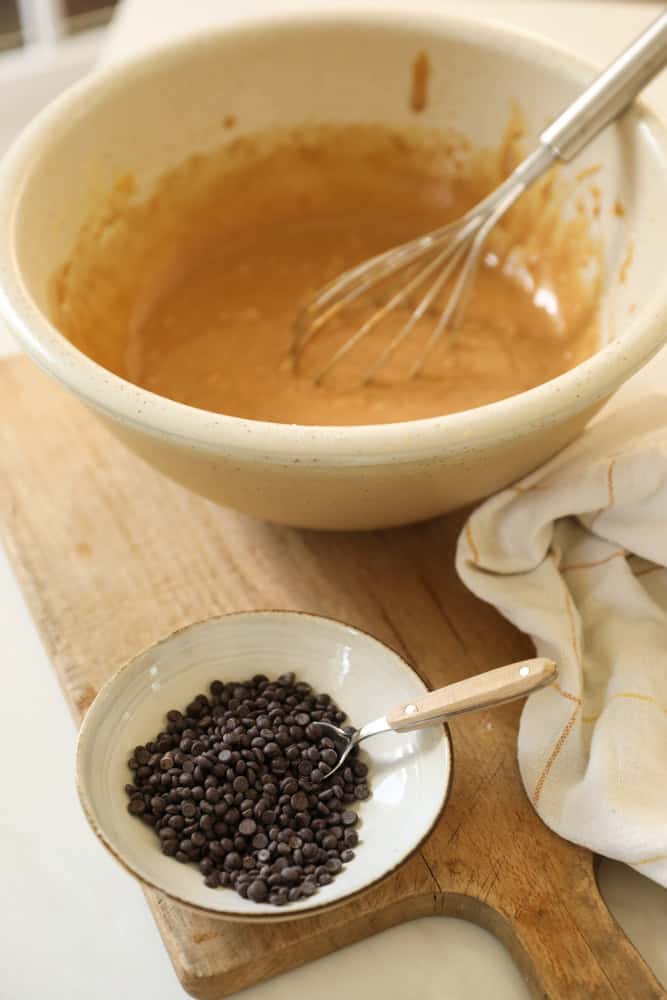 Muffin batter in a large bowl, with mini chocolate chips in another bowl.