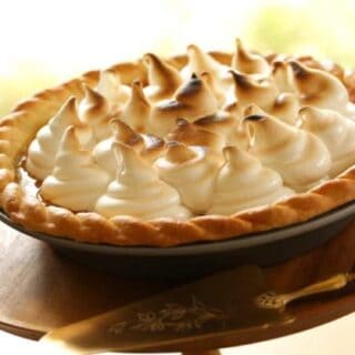 Pumpkin Pie with Marshmallow Topping on a wooden cake stand with a gold cake server