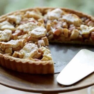 Apple Tart with Raisins and Walnuts on a cake stand with a slice taken out of it and a silver cake server