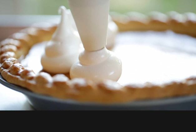 Piping Marshmallow topping onto a pumpkin pie