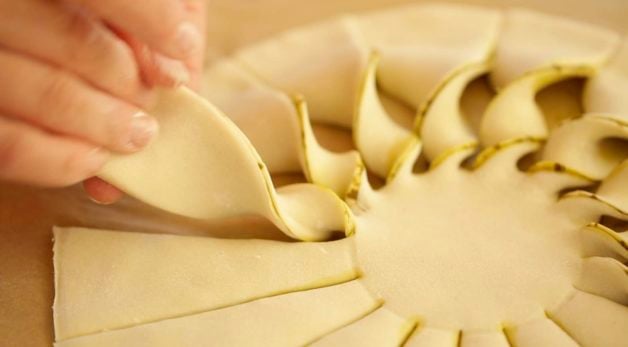 Twisting puff pastry sun rays on a cutting board for a Tarte au soleil