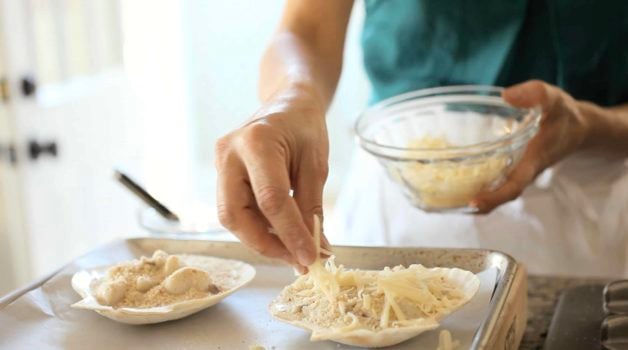 cheese sprinkled on top of Coquilles St Jacques Scallop Gratin