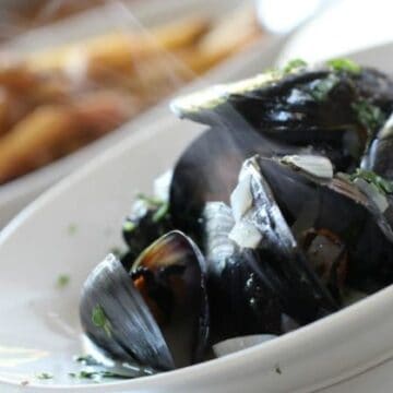 A bowl steaming mussels with french fries in the background