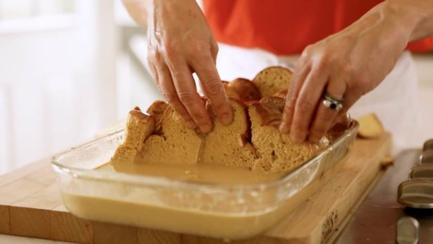 Arranging bread in casserole dish for a Gingerbread French Toast with Cinnamon Syrup Casserole