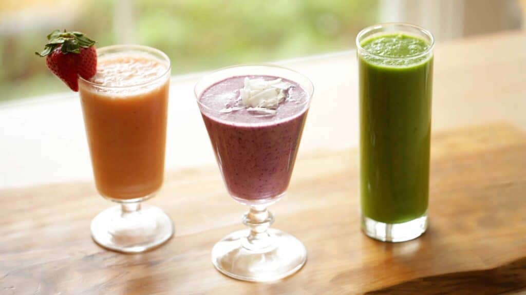  Breakfast Smoothies on cutting board including a tropical breakfast smoothie, a Green Breakfast Smoothie and a Blueberry Smoothie