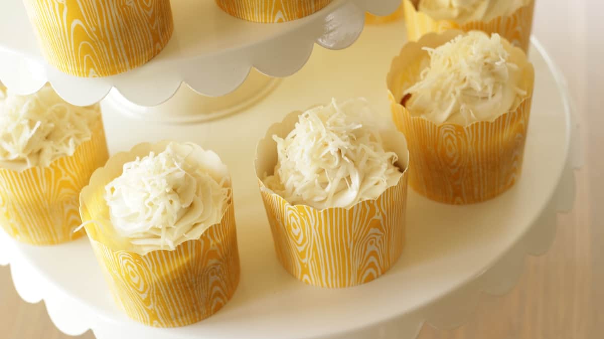 Coconut cupcakes in yellow liners on a cake stand
