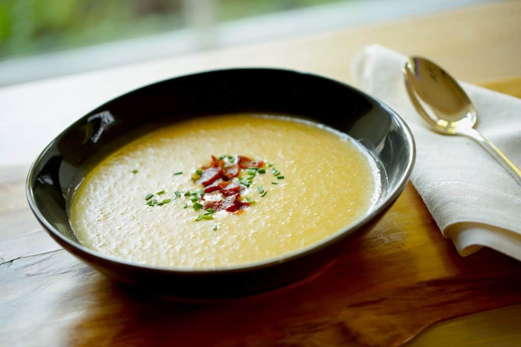 Potato Cheddar Bacon Soup in a black bowl with spoon and napkin