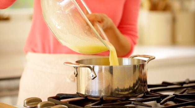 Pouring egg mixture into a pot on a cooktop