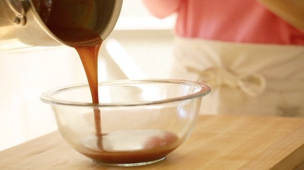 pouring caramel from a pot into a clear bowl