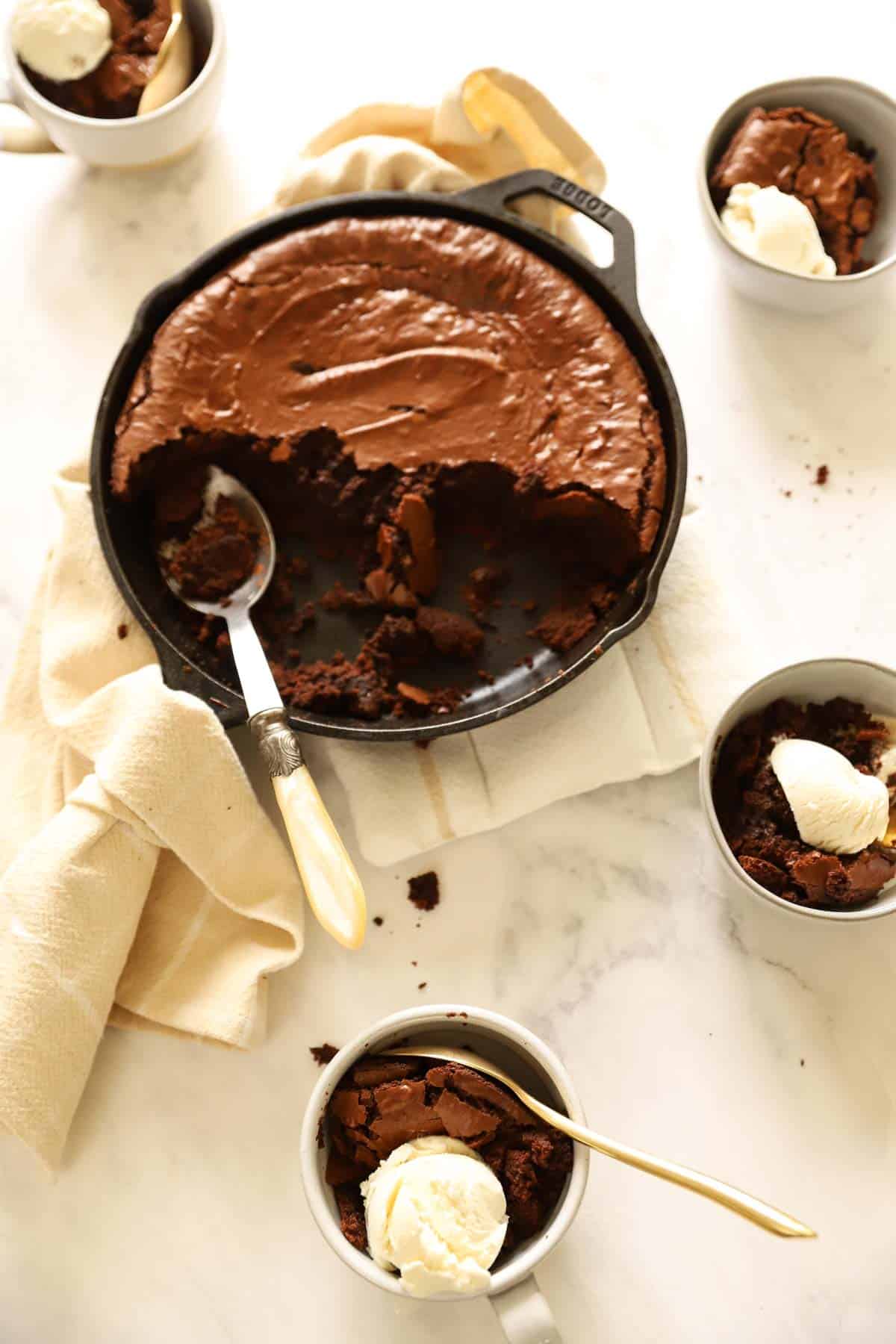 a chocolate skillet cake and 3 bowls served with cake and ice cream