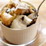 Spoon taking a bite of a Banana Bread Pudding with Chocolate Chunks drizzled with lightly whipped whipped cream